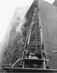 Fire engine with ladder up burning building