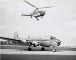 Low angle view of a helicopter in flight and an airplane at an airport, Sikorsky Helicopter, Douglas DC-4
