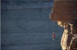 Man hanging from a rope on the edge of a cliff