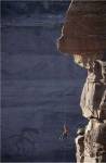 Man hanging from a rope on the edge of a cliff