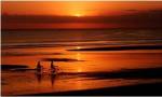Silhouette of a young couple cycling on the beach