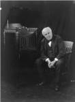 Thomas Edison, seated beside phonograph